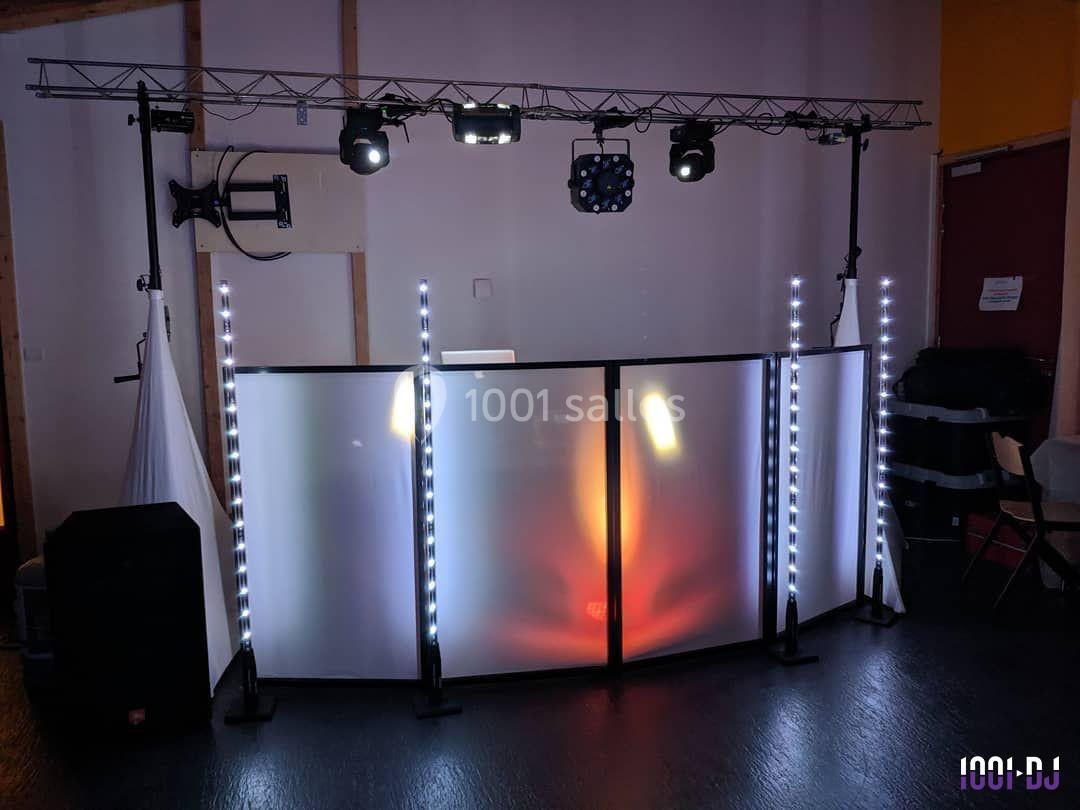 Structure de DJ avec éclairage LED coloré et panneaux translucides dans une salle sombre.