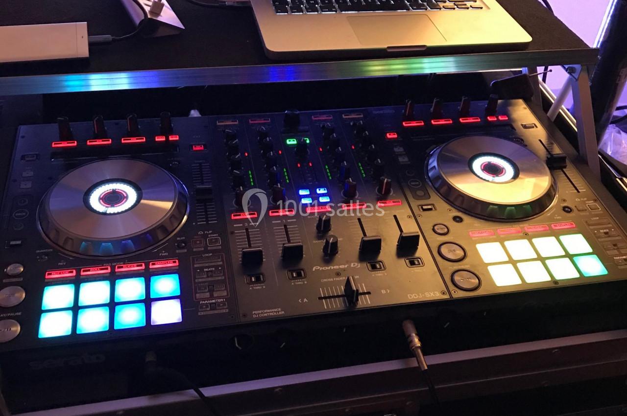 Table de mixage DJ avec platines lumineuses et un ordinateur portable affichant un logiciel de mixage.