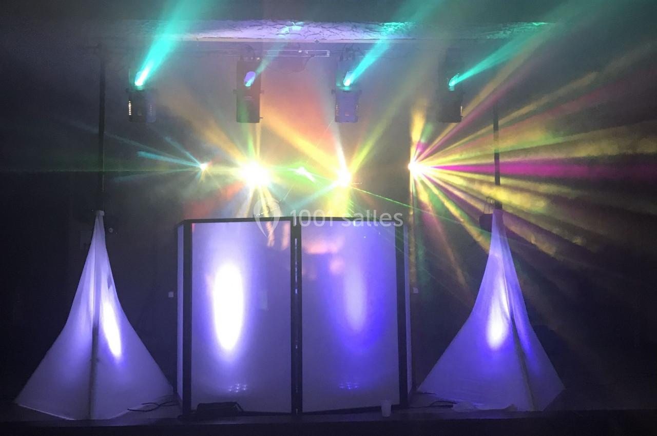 Jeu de lumières colorées sur une scène avec une structure centrale et deux éléments triangulaires éclairés.