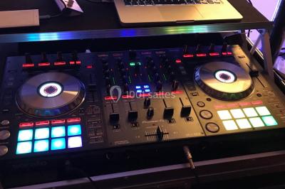 Table de mixage DJ avec platines lumineuses et un ordinateur portable affichant un logiciel de mixage.