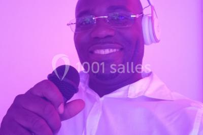 Console de DJ éclairée en bleu et rouge, installée dans une salle vitrée avec des invités en arrière-plan.