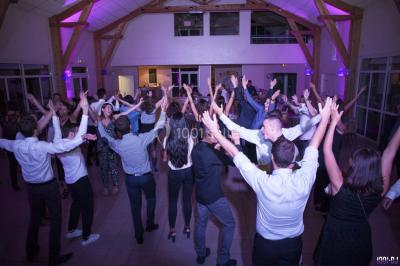 Console de DJ éclairée en bleu et rouge, installée dans une salle vitrée avec des invités en arrière-plan.