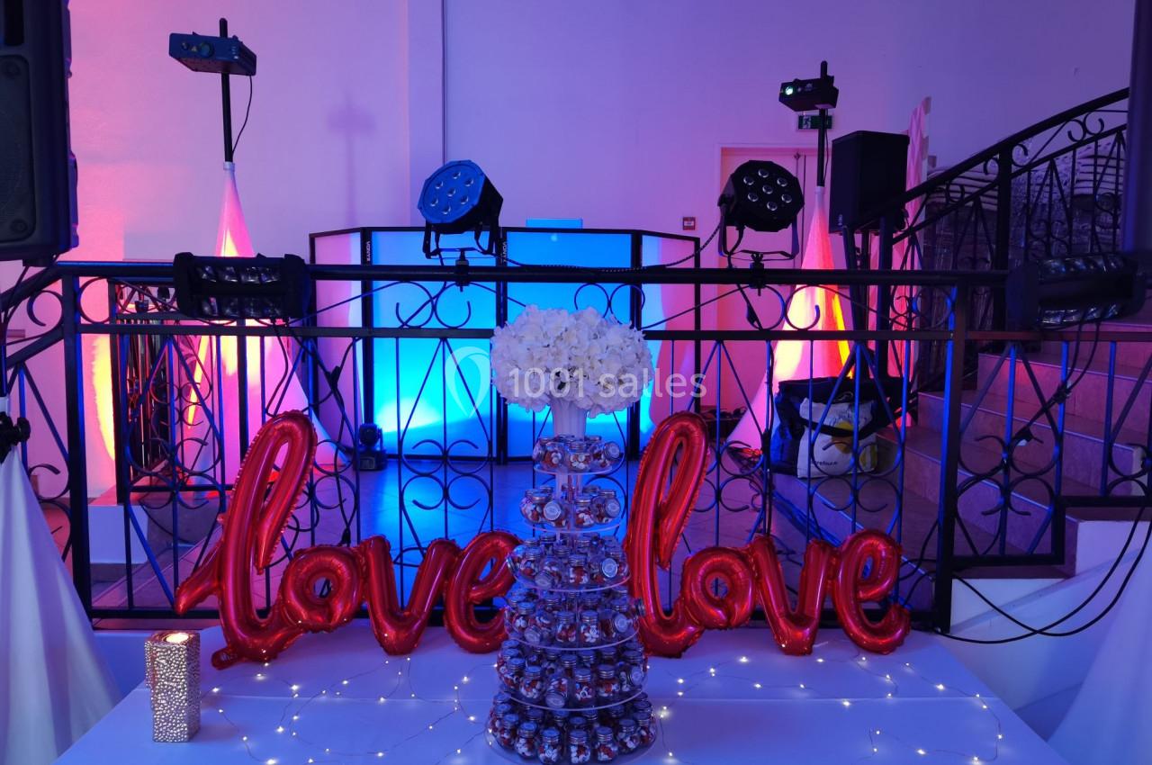 Décoration de fête avec ballons rouges ’love’, guirlande lumineuse, bouquet de fleurs blanches et présentoir de douceurs.