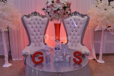 Console de DJ éclairée en bleu et rouge, installée dans une salle vitrée avec des invités en arrière-plan.