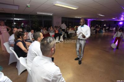 Console de DJ éclairée en bleu et rouge, installée dans une salle vitrée avec des invités en arrière-plan.