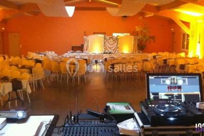 Console de DJ éclairée en bleu et rouge, installée dans une salle vitrée avec des invités en arrière-plan.