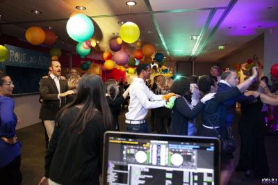 Console de DJ éclairée en bleu et rouge, installée dans une salle vitrée avec des invités en arrière-plan.