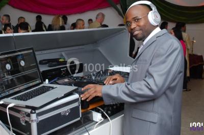 Console de DJ éclairée en bleu et rouge, installée dans une salle vitrée avec des invités en arrière-plan.