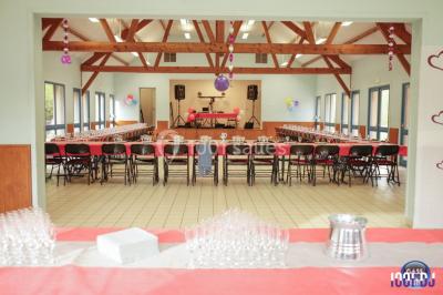 Console de DJ éclairée en bleu et rouge, installée dans une salle vitrée avec des invités en arrière-plan.