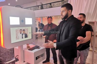 Console de DJ éclairée en bleu et rouge, installée dans une salle vitrée avec des invités en arrière-plan.