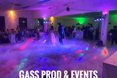 Console de DJ éclairée en bleu et rouge, installée dans une salle vitrée avec des invités en arrière-plan.