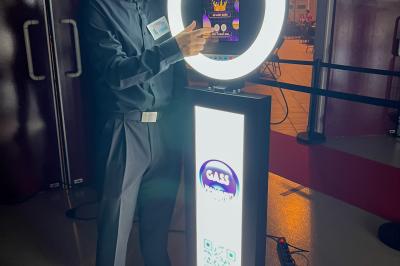 Salle de réception éclairée avec des lumières colorées, vue depuis une table de DJ équipée d'un ordinateur et de platines.