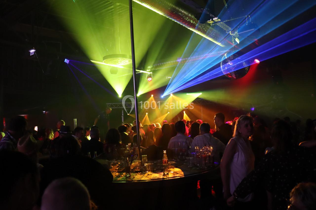 Personnes dans une discothèque avec des jeux de lumière colorés, une piste de danse et une ambiance festive.