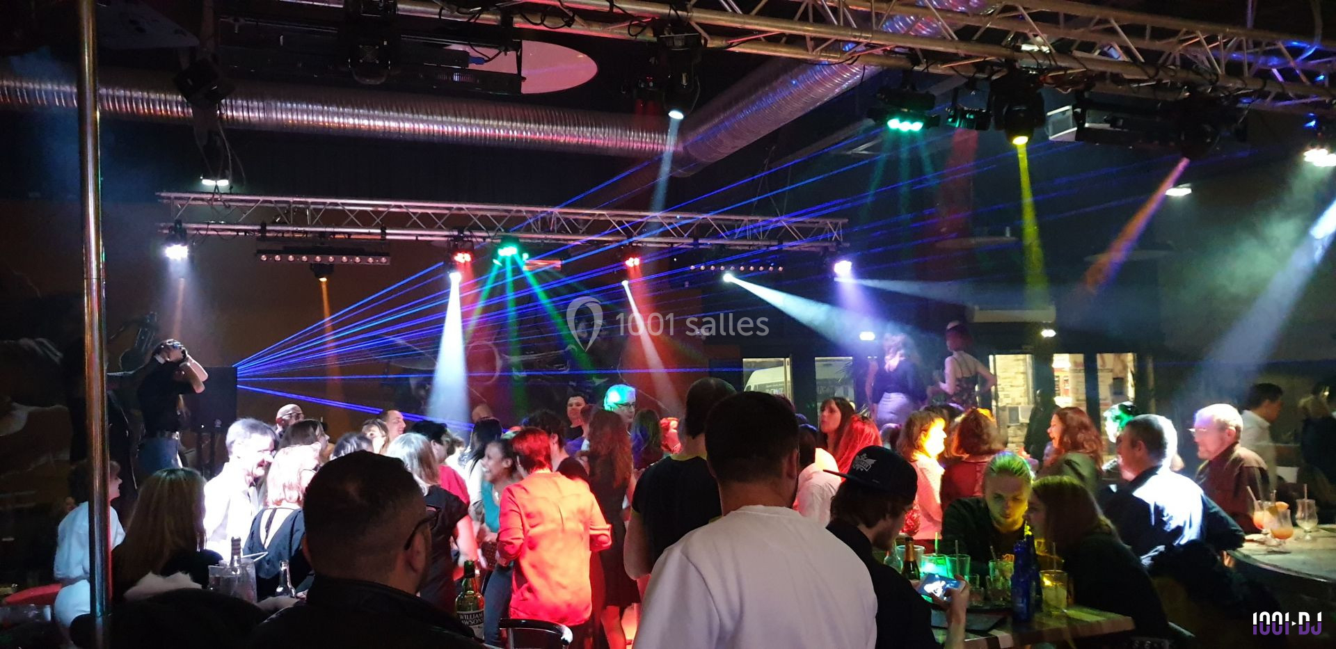 Groupe de personnes dans une discothèque avec jeux de lumières colorées et ambiance festive.