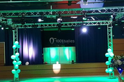 Vue depuis une table de mixage sur une salle éclairée par des lumières colorées, avec des invités assis et debout.