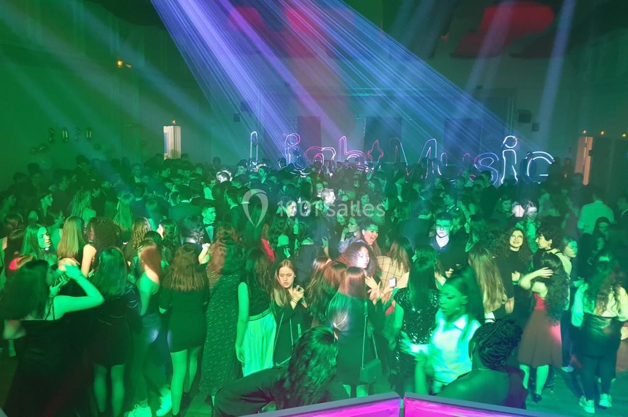 Groupe de personnes dansant sous des lumières colorées dans une salle sombre lors d'une soirée festive.