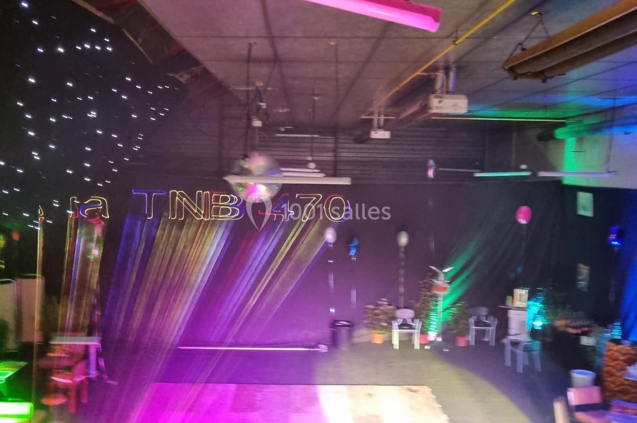 Salle décorée avec des lumières colorées, des étoiles suspendues et des lettres ’TNB 470’ illuminées.