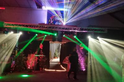 Vue depuis une table de mixage sur une salle éclairée par des lumières colorées, avec des invités assis et debout.