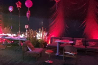 Vue depuis une table de mixage sur une salle éclairée par des lumières colorées, avec des invités assis et debout.