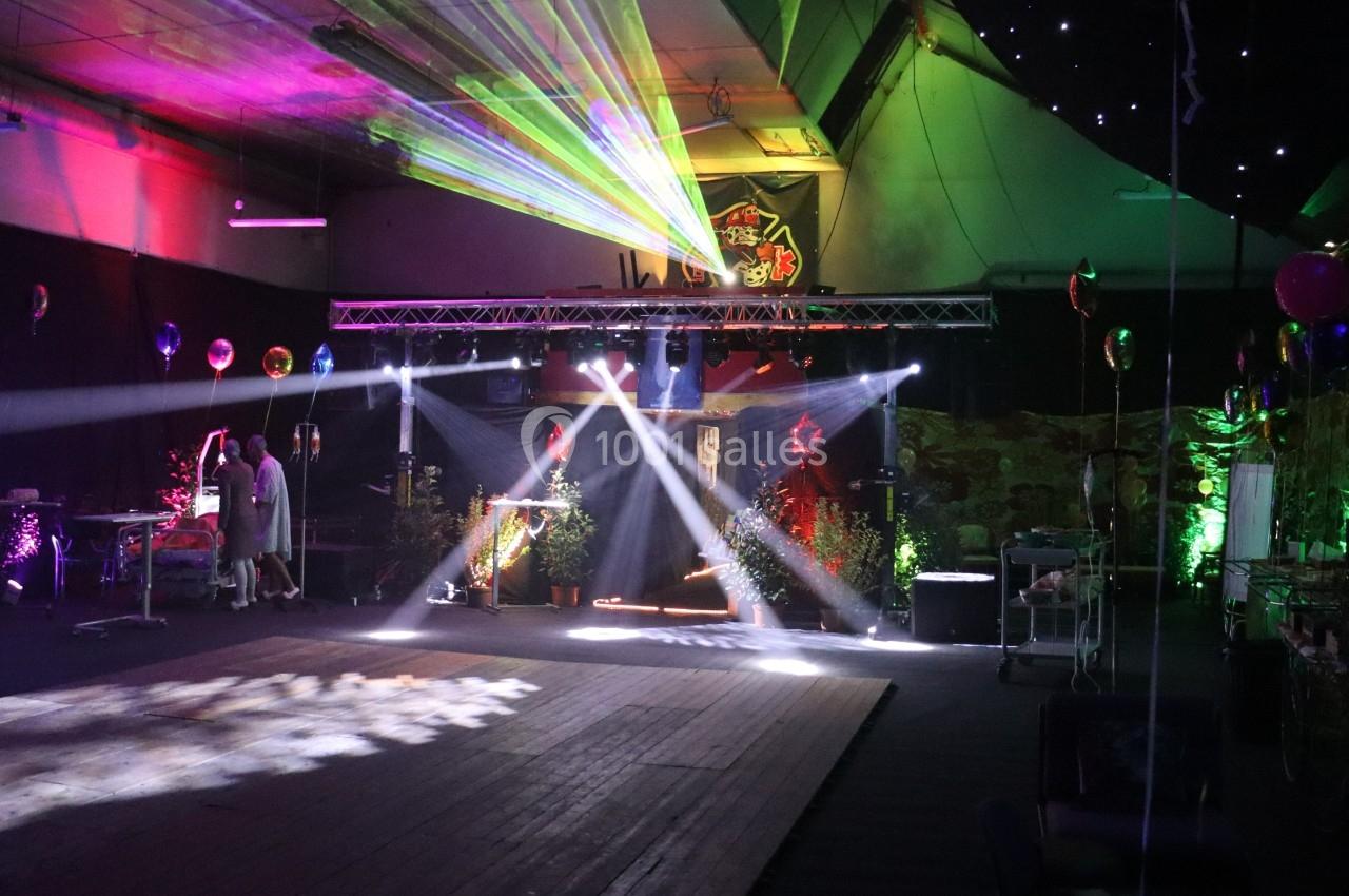 Salle décorée avec des lumières colorées, des lasers et des ballons, préparée pour un événement festif.