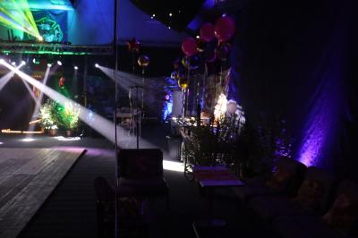 Vue depuis une table de mixage sur une salle éclairée par des lumières colorées, avec des invités assis et debout.