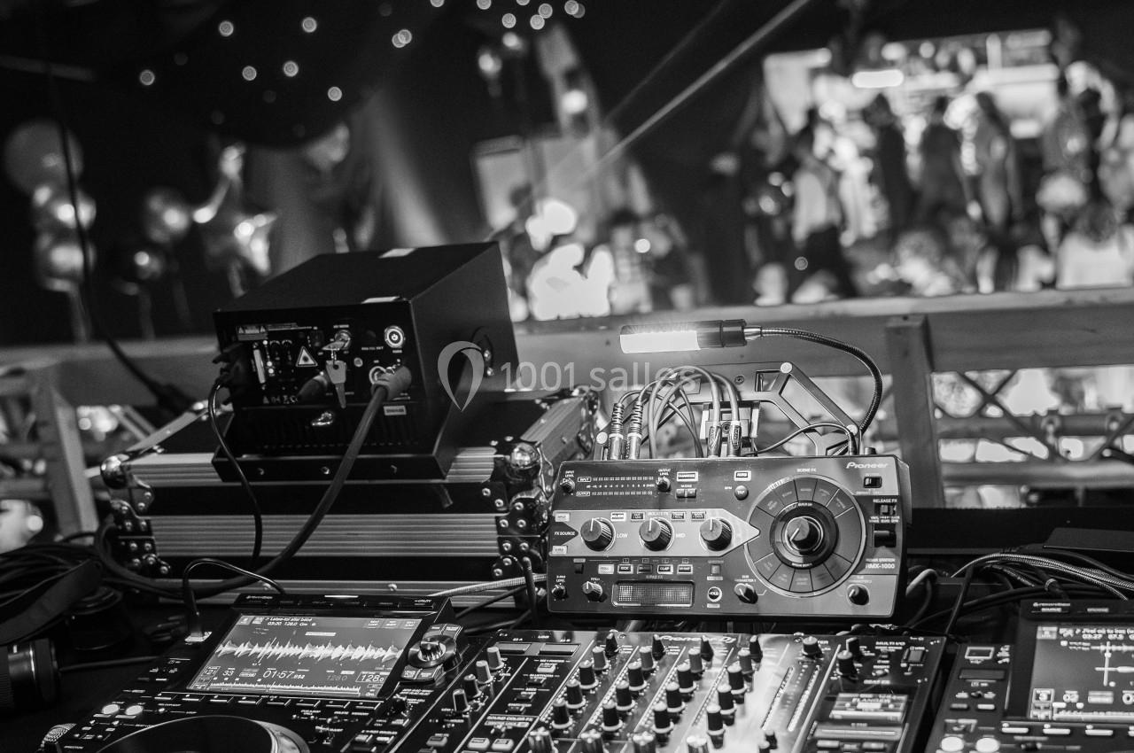 Console de mixage DJ avec platines et équipements audio dans une ambiance de fête sous des lumières tamisées.
