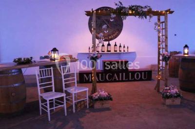 Table dressée avec des verres, tasses à café, un menu, un ordinateur portable ouvert et des chandeliers en arrière-plan.