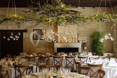 Table dressée avec des verres, tasses à café, un menu, un ordinateur portable ouvert et des chandeliers en arrière-plan.