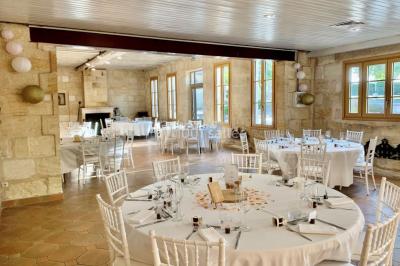 Table dressée avec des verres, tasses à café, un menu, un ordinateur portable ouvert et des chandeliers en arrière-plan.