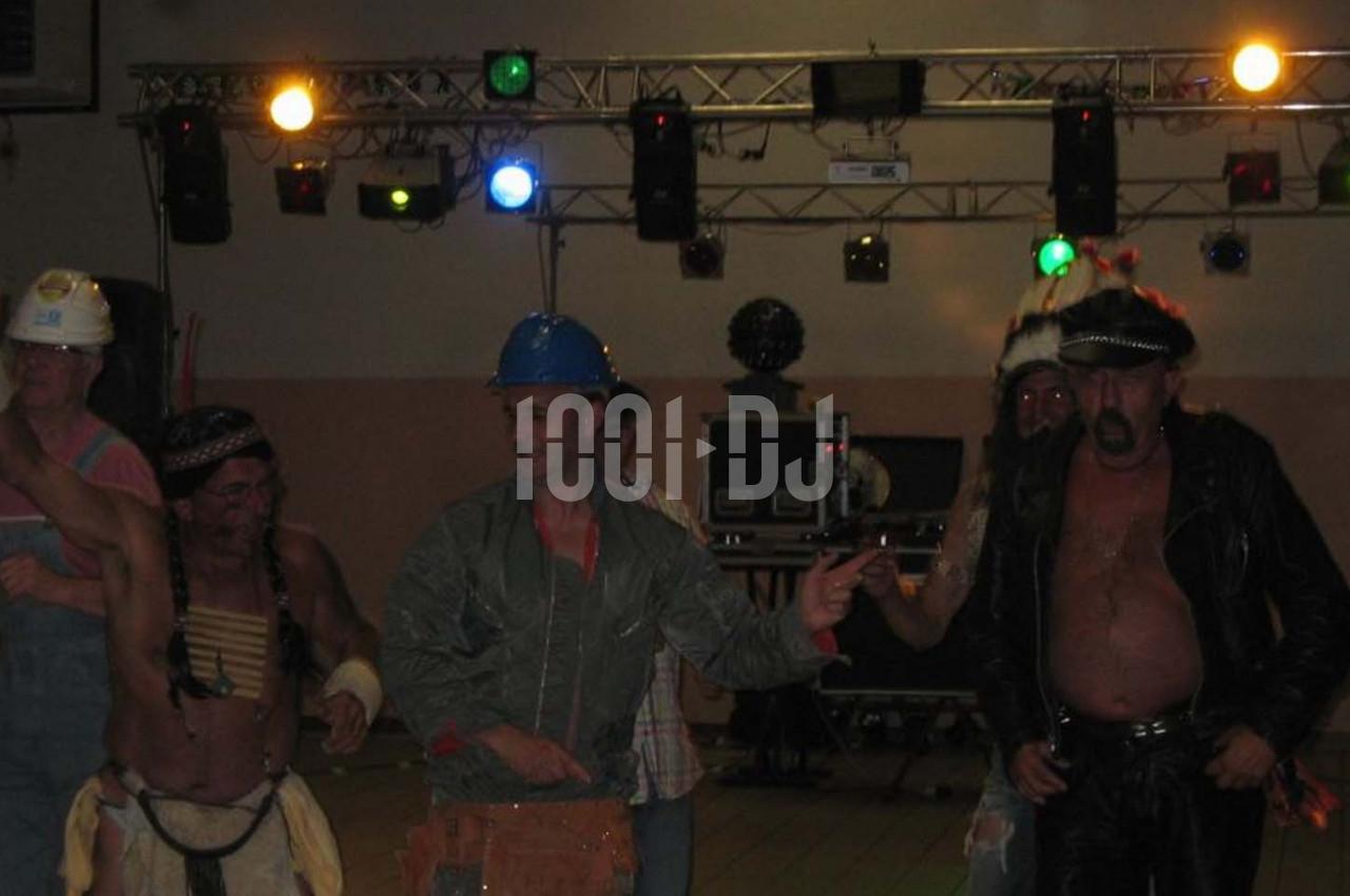 Des personnes déguisées, dont un ouvrier et un motard, dansent sous des éclairages colorés dans une salle.