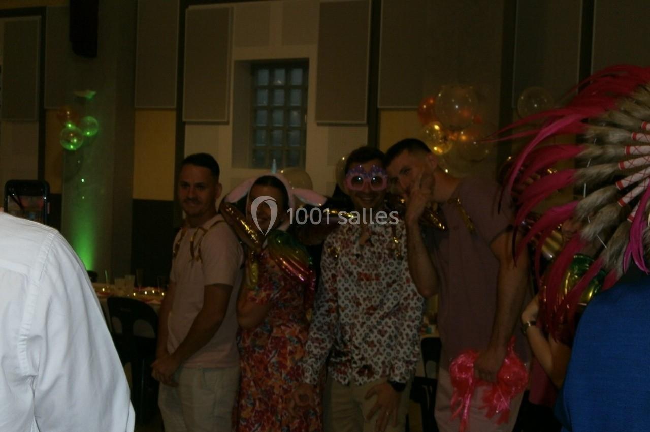 Des personnes déguisées posent ensemble dans une salle décorée avec des ballons et des guirlandes.