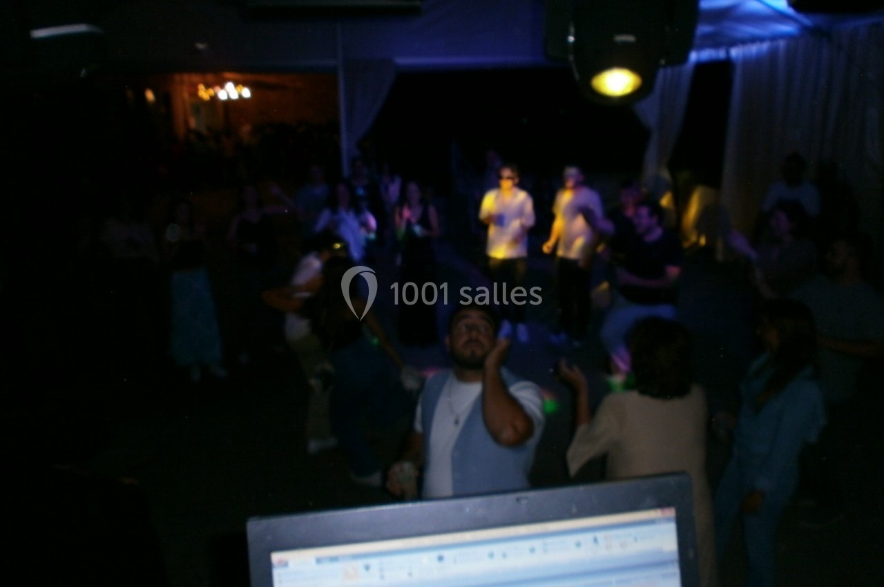 Groupe de personnes dansant dans une ambiance sombre avec éclairage coloré, vu depuis une table de mixage.