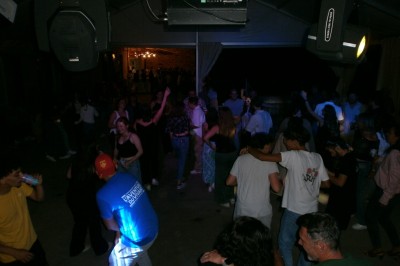 Groupe de personnes dansant sous une tente éclairée, ambiance festive avec lumières colorées.