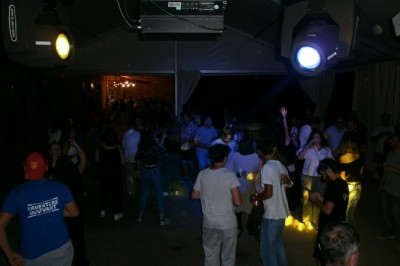 Groupe de personnes dansant sous une tente éclairée, ambiance festive avec lumières colorées.