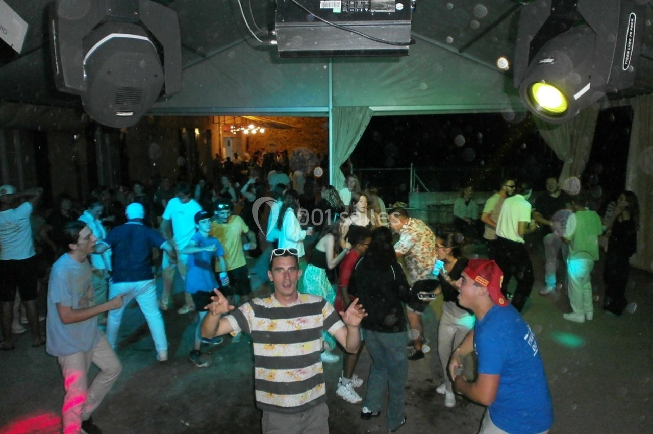 Groupe de personnes dansant sous une tente éclairée, ambiance festive avec lumières colorées.