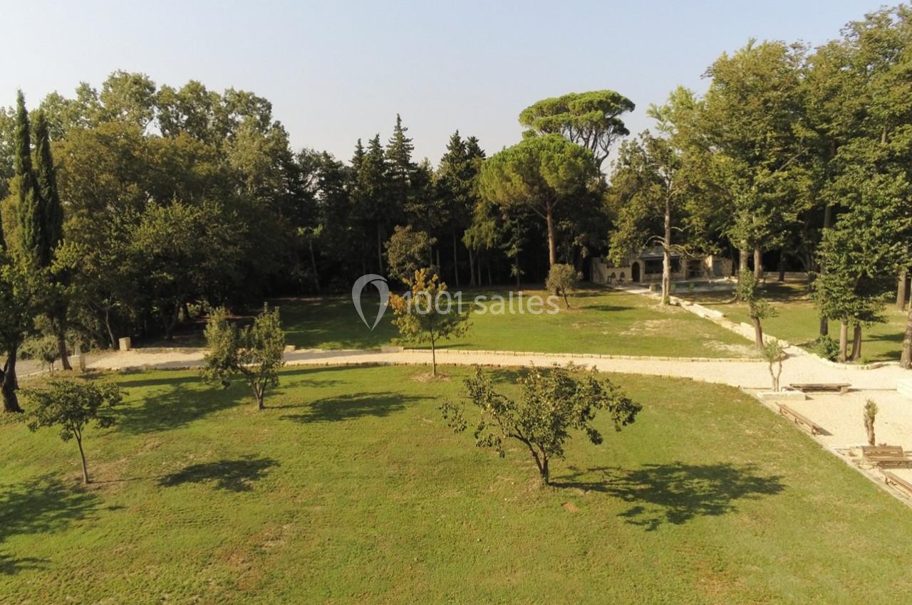 Vue aérienne d'un parc avec pelouse, arbres dispersés et chemins en gravier sous un ciel dégagé.