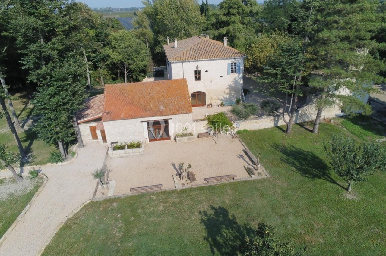 Vue aérienne d'une maison en pierre avec toit en tuiles, entourée d'arbres et d'un espace extérieur aménagé.