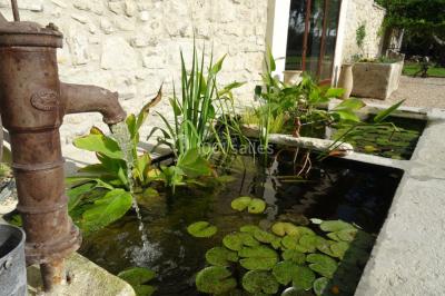 Salle de bain avec douche à l'italienne, lavabo double vasque, miroir éclairé et toilettes sur carrelage en terre cuite.