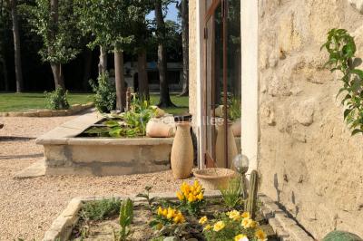 Salle de bain avec douche à l'italienne, lavabo double vasque, miroir éclairé et toilettes sur carrelage en terre cuite.