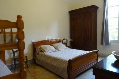 Salle de bain avec douche à l'italienne, lavabo double vasque, miroir éclairé et toilettes sur carrelage en terre cuite.