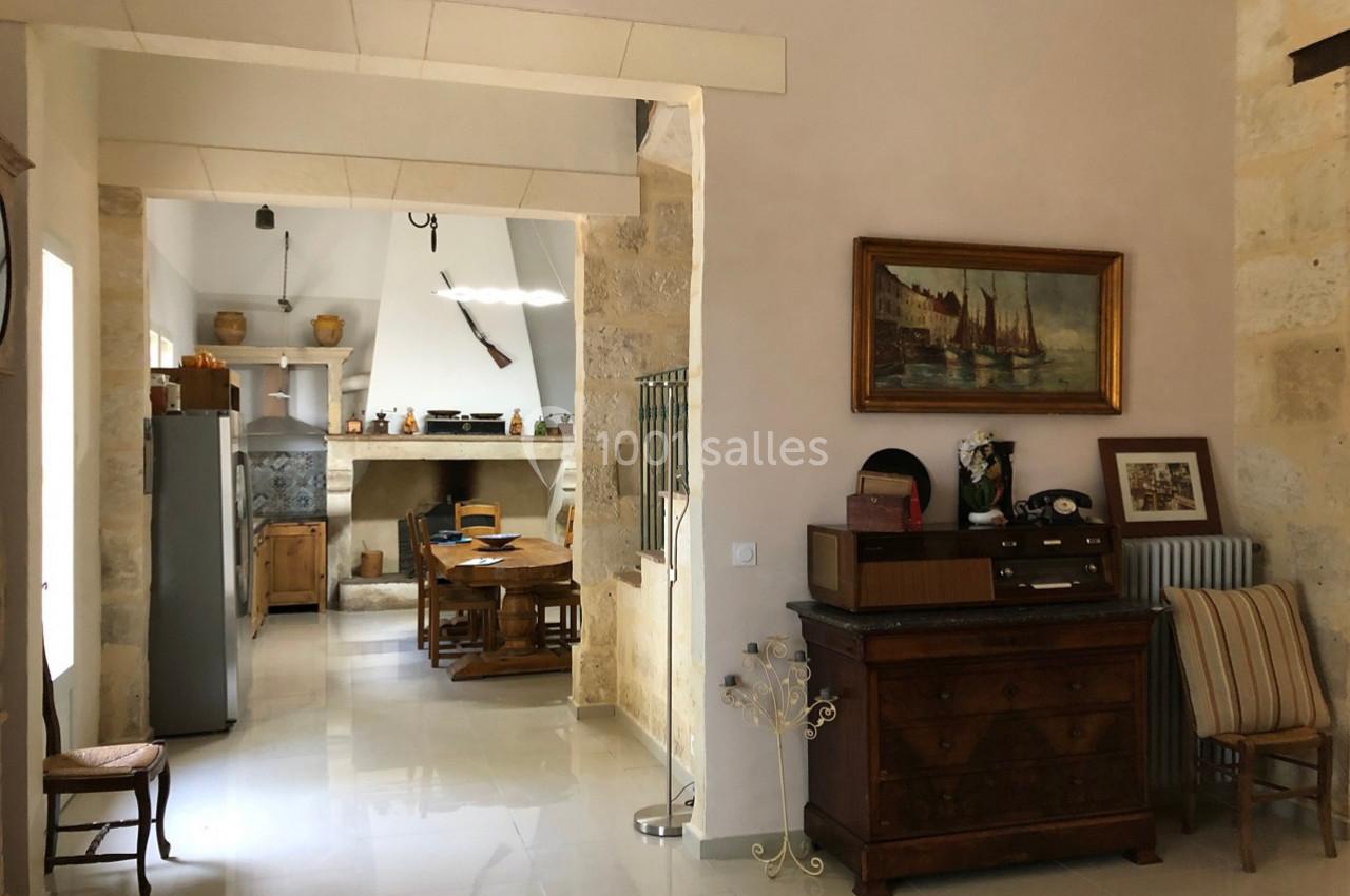 Intérieur d'une maison avec cuisine ouverte, mobilier en bois, tableau mural et décoration rustique.