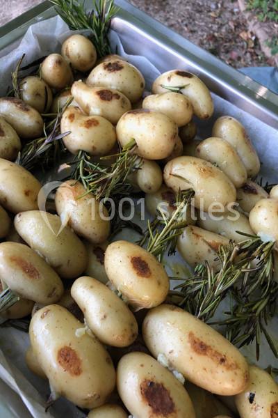 Pommes de terre rôties avec des branches de romarin sur une plaque recouverte de papier cuisson.