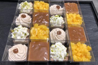 Assortiment de verrines sucrées avec mousse, caramel, mangue et chantilly, disposées sur un plateau noir.