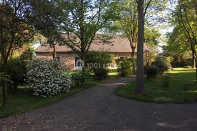 Chaise en bois marquée ’Gîte de la Barre’ dans un jardin verdoyant près d'une maison en pierre et crépi.