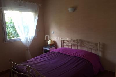 Chaise en bois marquée ’Gîte de la Barre’ dans un jardin verdoyant près d'une maison en pierre et crépi.