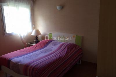 Chaise en bois marquée ’Gîte de la Barre’ dans un jardin verdoyant près d'une maison en pierre et crépi.