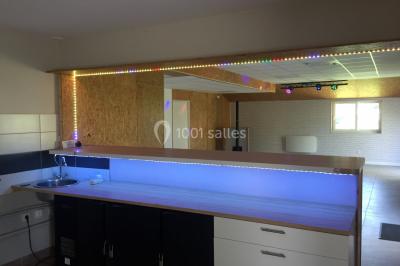 Chaise en bois marquée ’Gîte de la Barre’ dans un jardin verdoyant près d'une maison en pierre et crépi.