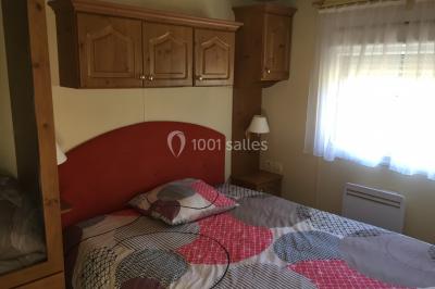 Chaise en bois marquée ’Gîte de la Barre’ dans un jardin verdoyant près d'une maison en pierre et crépi.