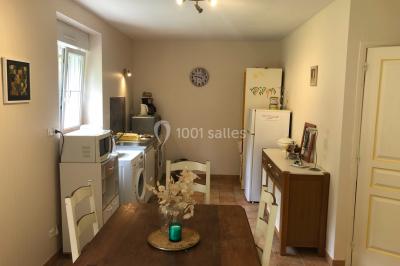 Chaise en bois marquée ’Gîte de la Barre’ dans un jardin verdoyant près d'une maison en pierre et crépi.