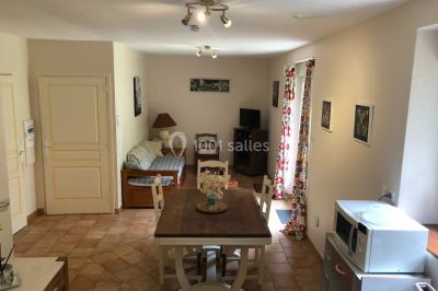 Chaise en bois marquée ’Gîte de la Barre’ dans un jardin verdoyant près d'une maison en pierre et crépi.